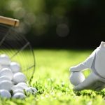 Hand hold golf ball with tee on green grass for practice